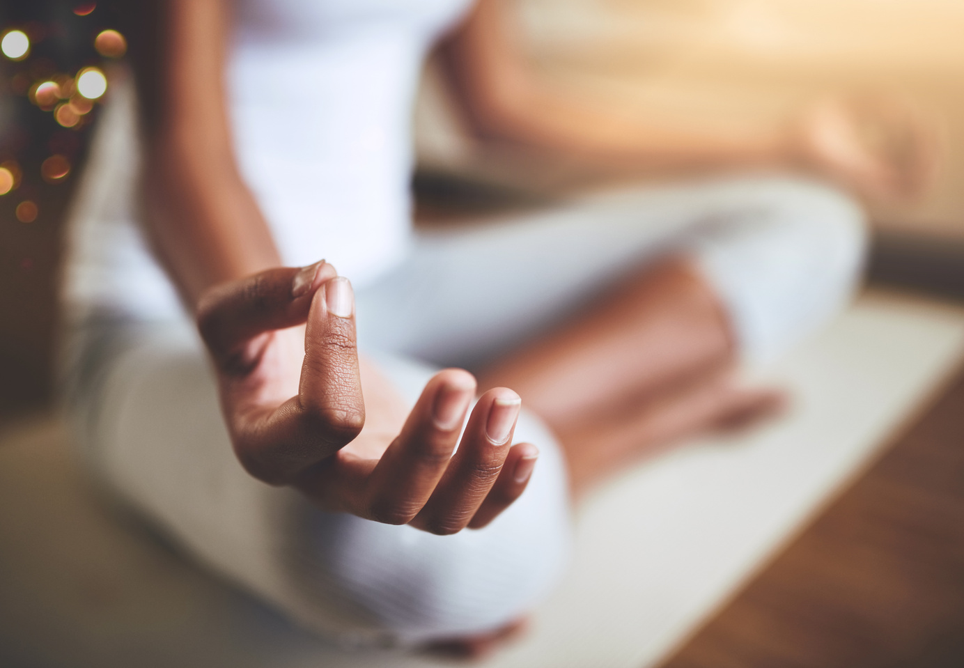 The hand of a black woman is in the chin mudra and resting on her knee to show her practicing meditation and mindfulness